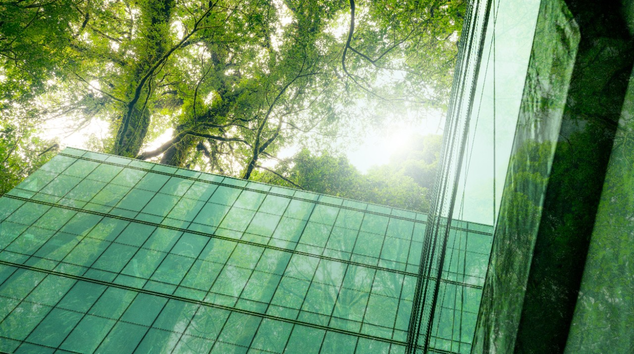 Eco-friendly building in modern city. Sustainable glass office building with trees for reducing CO2. Green architecture. Building with green environment. Sustainability corporate. Net zero emissions.