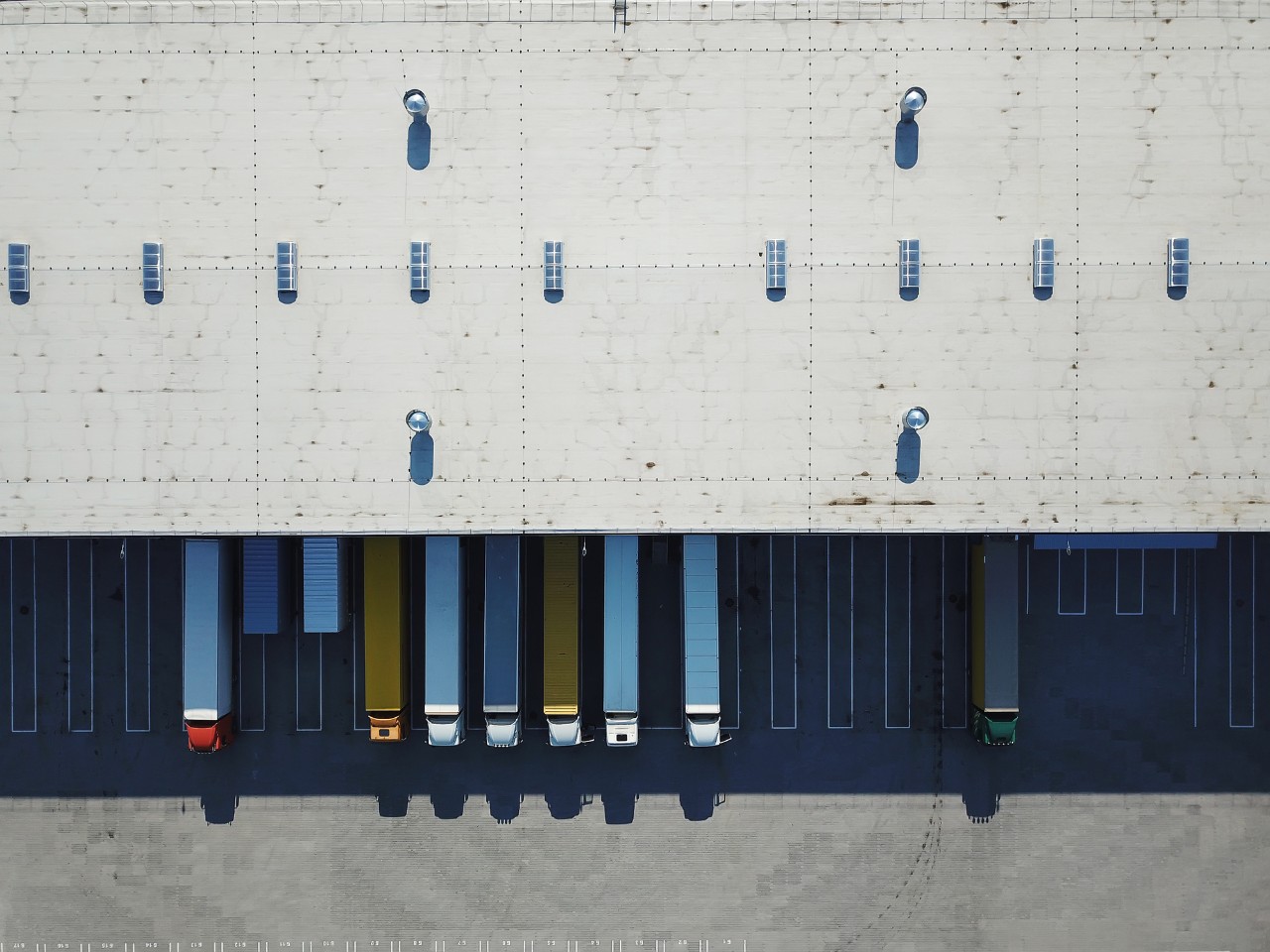 Aerial view of goods warehouse. Logistics center in industrial city zone from above. Aerial view of trucks loading at logistic center