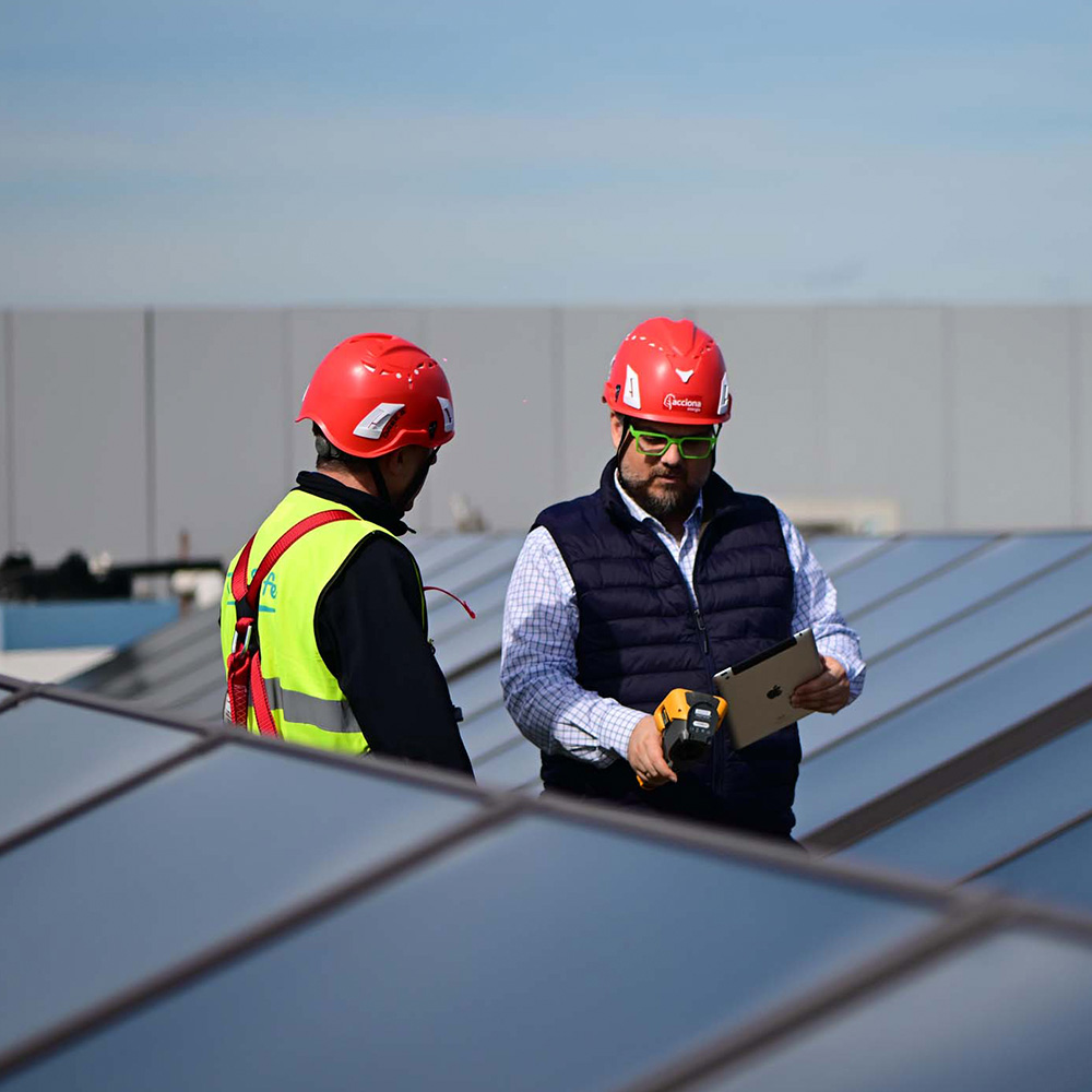Dos instaladores revisando los paneles solares de una azotea